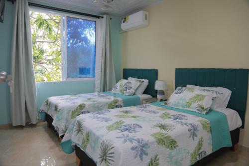 1 dormitorio con 2 camas y ventana en Posada Mango House en San Andrés
