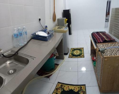 丹戎馬林的住宿－Homestay D'Mama Īfor mūslimĪ，厨房配有水槽和地面带垫子的台面。