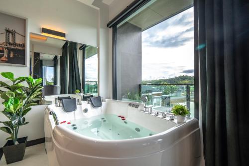 Pim Pool Villa Nan في نان: حوض استحمام في حمام مع نافذة كبيرة
