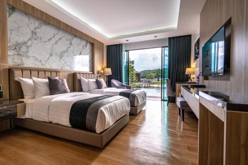 a hotel room with two beds and a television at Pim Pool Villa Nan in Nan