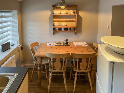 cocina con mesa de madera y sillas en Smithy Cottage en Keldhead