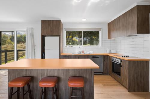 Myrtle Cottage في أريز إنليت: مطبخ مع قمم منضدة خشبية وكراسي برتقالية