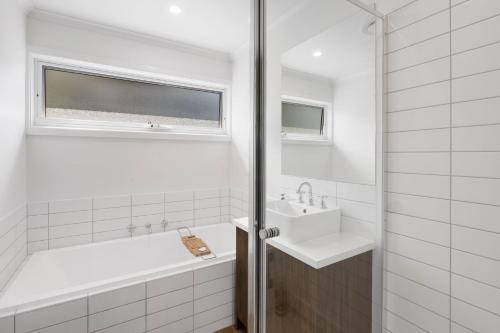 a white bathroom with a tub and a sink at Myrtle Cottage in Aireys Inlet