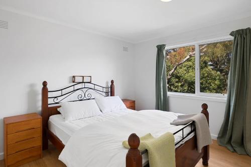 a bedroom with a large bed and a window at Myrtle Cottage in Aireys Inlet