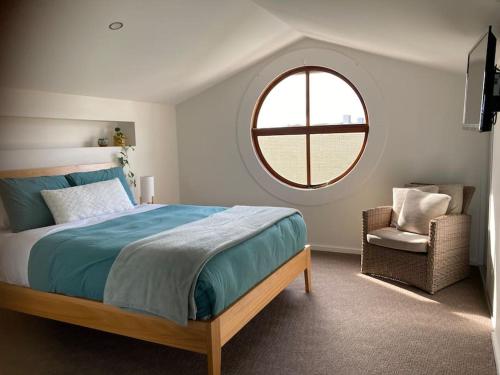 a bedroom with a bed and a window and a chair at 12 Rocks Beach View Loft Central Port Campbell in Port Campbell