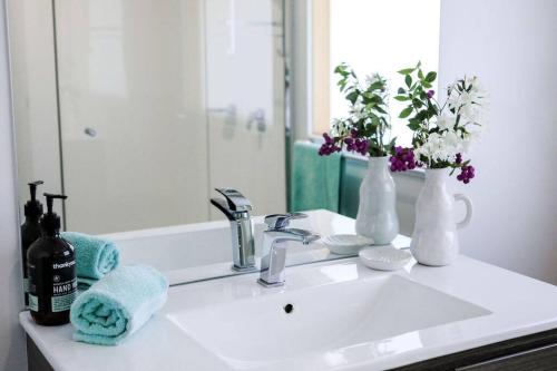 a bathroom sink with a bottle of wine and flowers at 12 Rocks Beach View Loft Central Port Campbell in Port Campbell