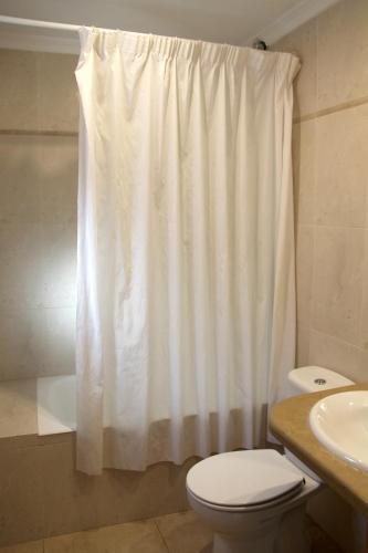 a bathroom with a white shower curtain and a toilet at Hostal Restaurante La Masía in Villareal