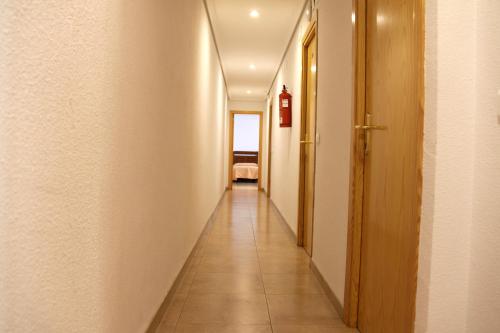 a hallway with white walls and a long hall with a red fire extinguisher at Hostal Restaurante La Masía in Villareal