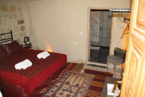 a bedroom with a red bed with towels on it at CAPPADOCİA ST.NİNO'S GARDEN in Ortahisar