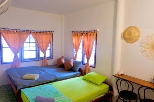 1 dormitorio con 2 camas y 2 ventanas en Lungkluay homestay, en Ko Kood