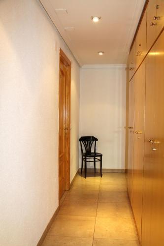 a hallway with a chair and a wooden door at Hostal Restaurante La Masía in Villareal