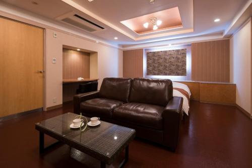a living room with a leather couch and a bed at Hotel Rea Tiare - Adult Only- in Himeji
