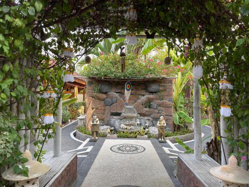 a garden with a fountain and a stone wall at Banana cottages in Gili Air