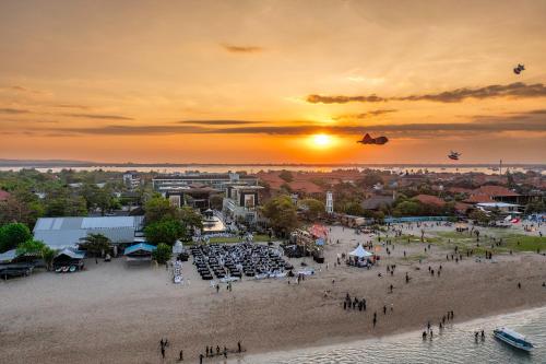 a group of people standing on a beach with planes in the sky at The Sakala Resort Bali All Suites in Nusa Dua