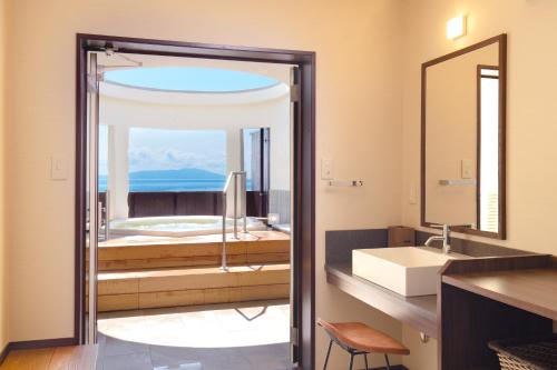 a bathroom with a tub and a sink and a mirror at Tsuruya Kisshotei in Higashiizu