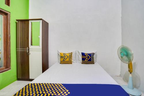 Schlafzimmer mit einem Bett mit einem Ventilator und Kissen in der Unterkunft OYO 91747 Gamping Homestay Syariah in Gresik