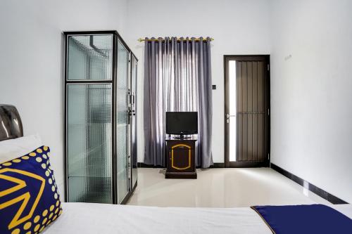 ein Schlafzimmer mit einem Bett und einem TV. in der Unterkunft SPOT ON 91745 Rumah Kost Gresik Syariah in Gresik