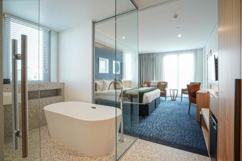 a bathroom with a bath tub and a bedroom at The Langlands Hotel in Invercargill