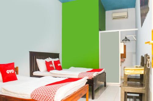 2 camas en una habitación con una pared verde en OYO 91769 Wisma Harapan Baik, en Kupang