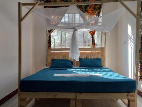 L&J Modern Backpackers Kigamboni Beach House في دار السلام: غرفة نوم مع سرير المظلة بالشراشف الزرقاء
