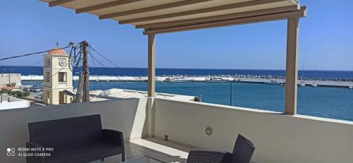 a balcony with a view of the water and a clock tower at Ioannas Endless Blue Apartment in Ierapetra