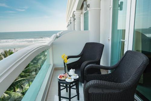 two chairs on a balcony with a view of the ocean at The Sailing Bay Beach Resort in Mui Ne