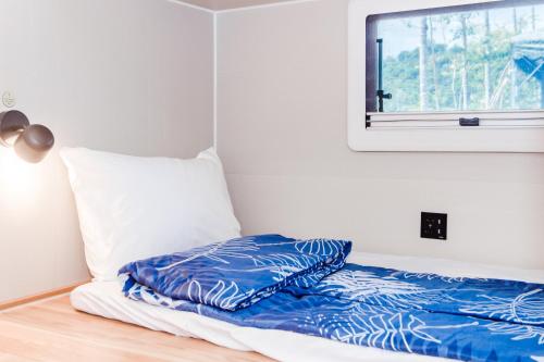 a bed with a blue pillow and a window at Tai  Ping  Shan Inn in Ta-hsi