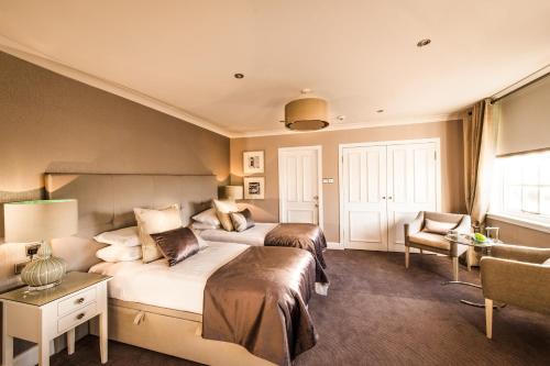a hotel room with two beds and a chair at Piersland House in Troon