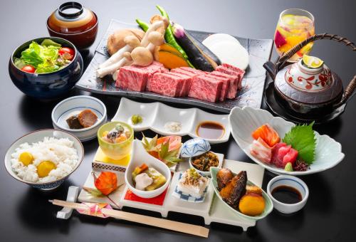 einen Tisch mit Teller mit Lebensmitteln und Schüsseln mit Lebensmitteln in der Unterkunft Yunotani Senkei in Totsukawa