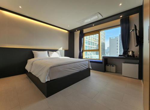 a bedroom with a large bed and a large window at Gold Stone Hotel in Busan