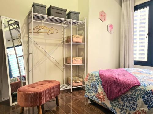 um quarto com um armário com uma cama e um banco em Tropical Home at SMDC Air Residences Makati em Manila