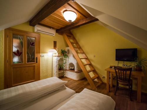 a bedroom with two beds and a desk with a television at Penzion a Restaurace U Johana in Zlín