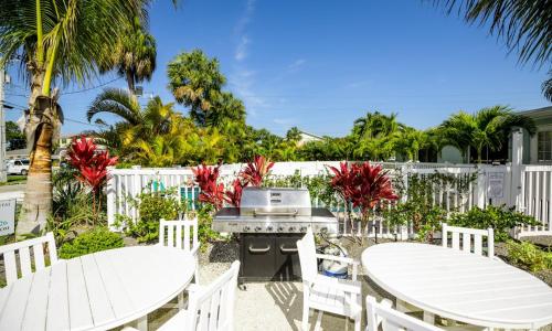 a patio with two tables and chairs and a grill at Driftwood Villas at Anna Maria Island Inn in Holmes Beach