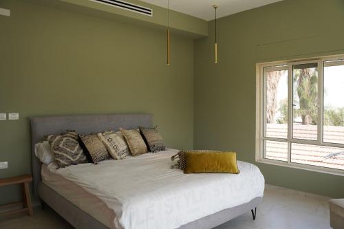 Cama en habitación verde con ventana en סיני 48 מלון דירות בוטיק, en Vered Yeriho