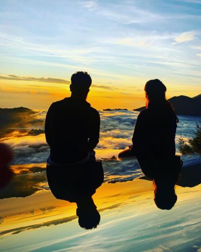 a man and woman sitting on the beach at sunset at Bali Astetic Villa and Hot Spring in Kintamani