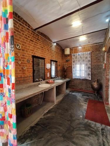 a bathroom with two sinks and a brick wall at Naurang Yatri Niwas in Garli