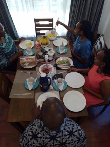 a group of people sitting around a table eating food at El Tessa garden/serviced apartment in Kisumu