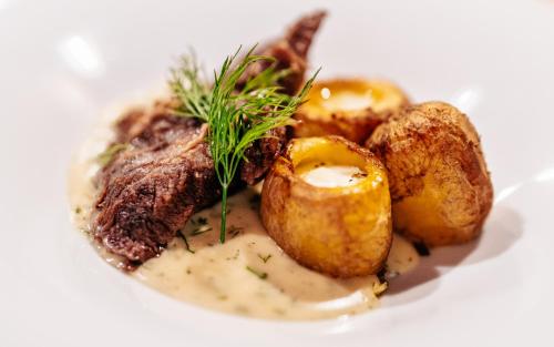 a plate of food with meat and potatoes on a white plate at Penzion a Restaurace U Johana in Zlín
