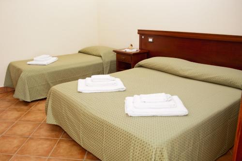 three beds in a room with towels on them at Agriturismo Valle dell'Etna in Roccella Valdemone