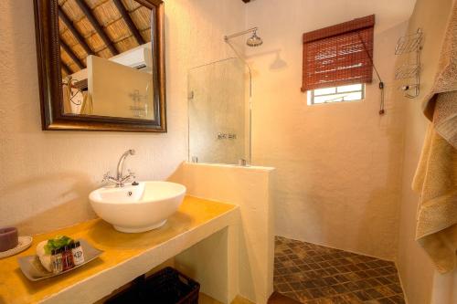 y baño con lavabo blanco y ducha. en Mvuradona Safari Lodge, en Marloth Park