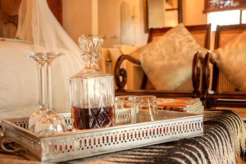 a tray with a bottle and glasses on a table at Mvuradona Safari Lodge in Marloth Park