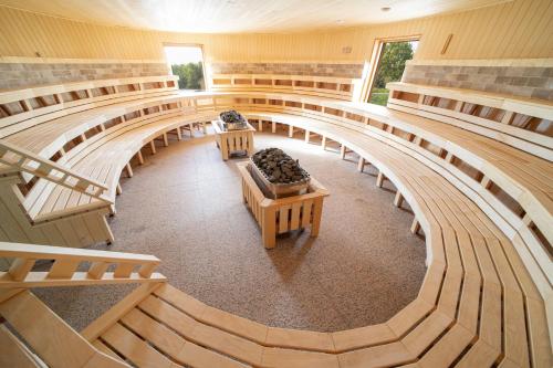 an empty auditorium with benches and tables in a building at MenDan Magic Spa & Wellness Hotel in Zalakaros