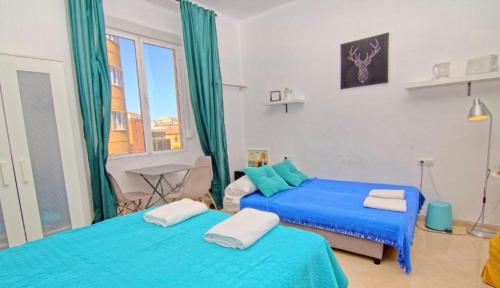 ein Schlafzimmer mit zwei Betten mit blauer Bettwäsche und einem Fenster in der Unterkunft Guests House Mercado Malaga in Málaga