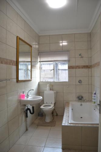 uma casa de banho com uma banheira, um WC e um lavatório. em Green Grove Villa em Centurion