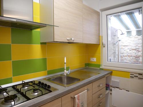 eine Küche mit einer Spüle, einem Herd und einem Fenster in der Unterkunft LondonSuite - nuovissimo mini Appartamento in Grado