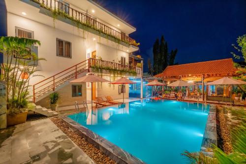 a swimming pool in front of a building at night at Alley Garden Homestay Hoi An in Hoi An