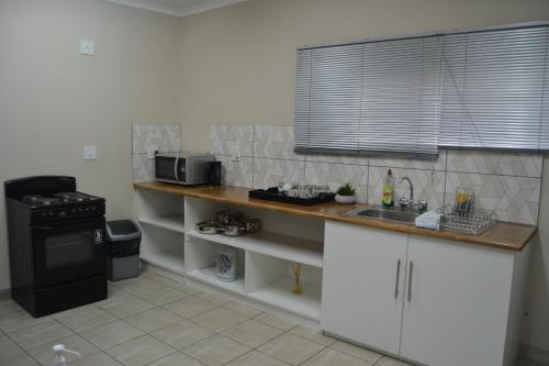 a kitchen with a counter with a sink and a microwave at Green Grove Villa in Centurion