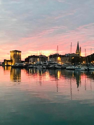 un port avec des bateaux dans l'eau au coucher du soleil dans l'établissement Appartement Saint Claude - Centre Port, à La Rochelle