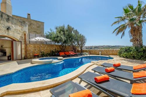a swimming pool with lounge chairs and a house at The Hamlet 2 Holiday Home in Għasri