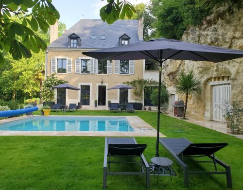 um guarda-sol e cadeiras junto a uma piscina em Domaine du Val Sauvage em Langeais